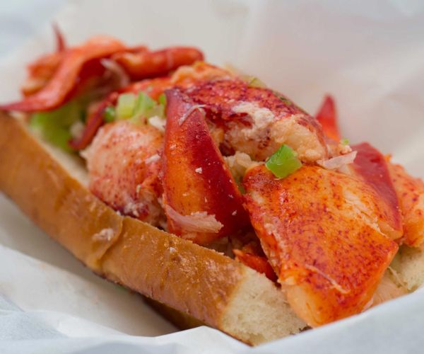 closeup of Sam's ChowderMobile famous Lobster Roll sandwich shows lots of fresh Maine lobster lightly tossed in warmed butter on a toasted bun
