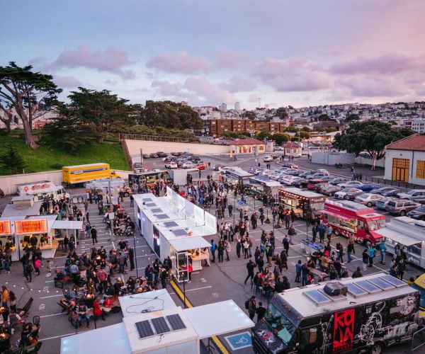 food trucks serving in San Francisco neighborhood parking lot during event at dusk